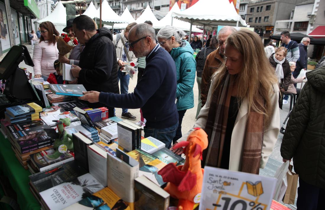 Dos homes i una dona miren llibres en una parada de la plaça de la Rotonda a Andorra la Vella.