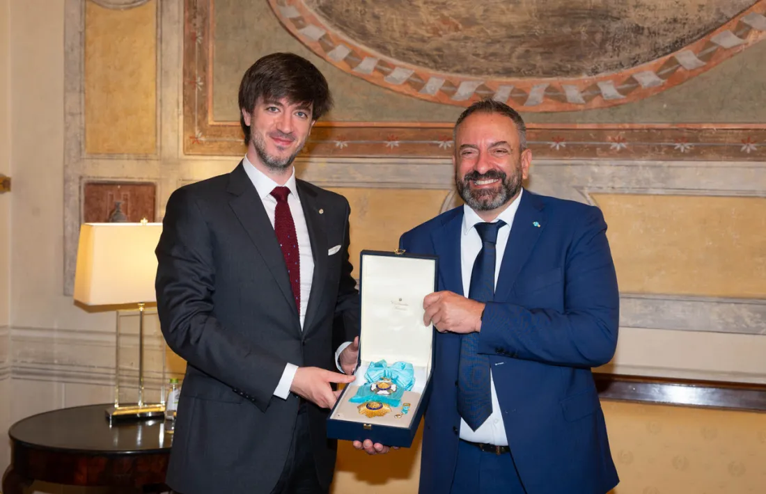 El secretari d’Estat de San Marino, Luca Beccari, rep el set complet de l’Orde de Carlemany – placa, banda, creu (que penja de la banda), miniatura i roseta– de mans del síndic general.