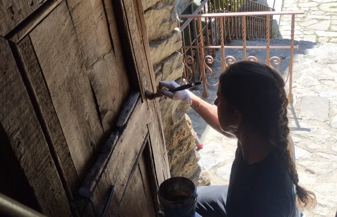  La restauradora Mireia Garcia impregna la porta amb un producte que no deixa capa. 