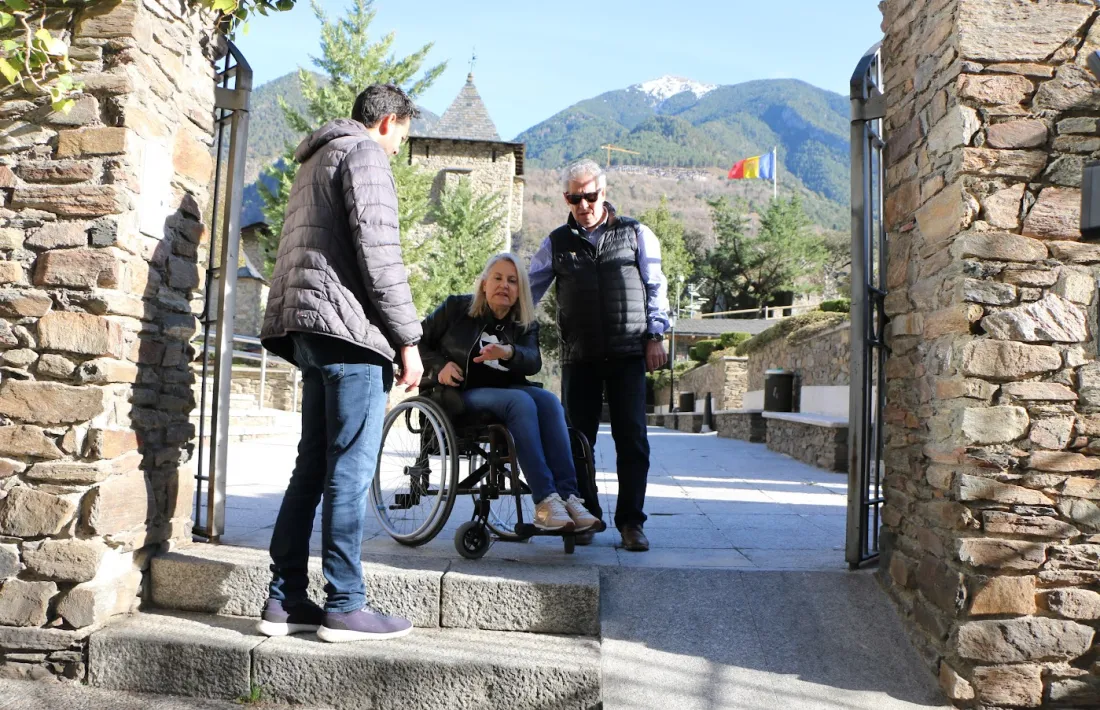 Una persona amb mobilitat reduïda davant d'unes escales i una rampa pronunciada.