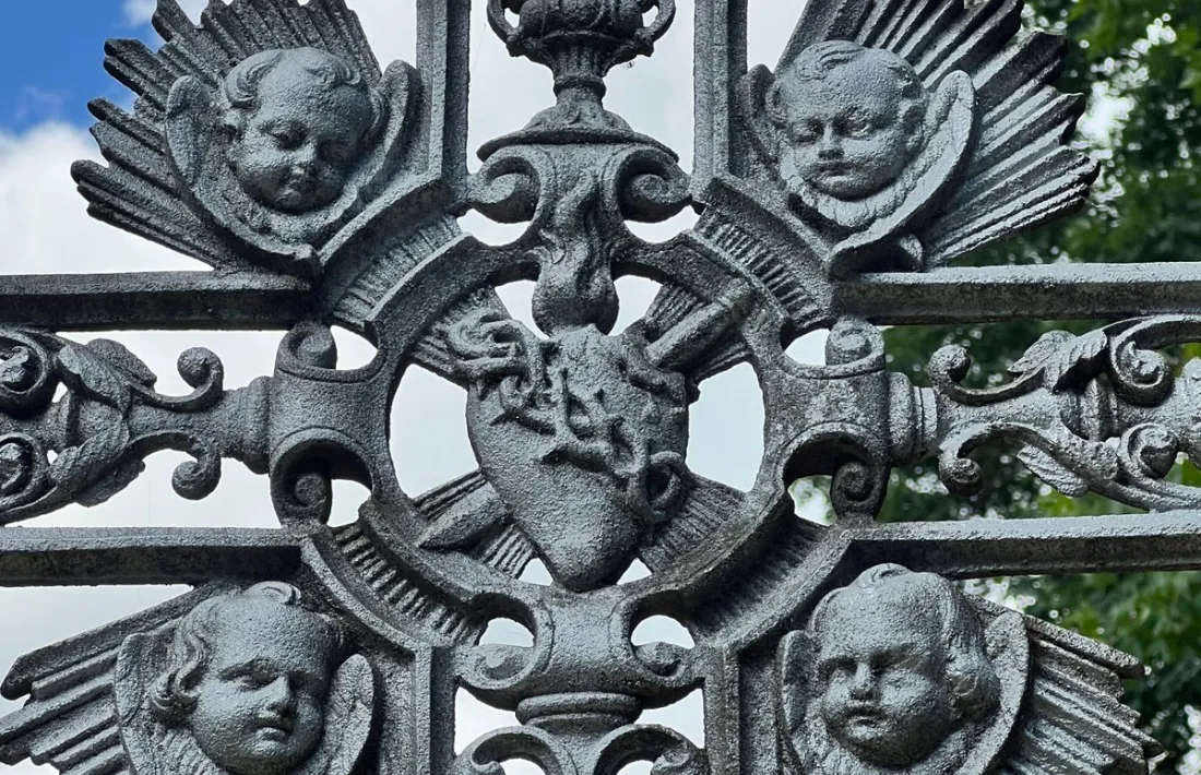 La decoració de la creu la formen els símbols de l'eucaristia, una colla d e querubins, i l'anagrama de la Mare de Deu.