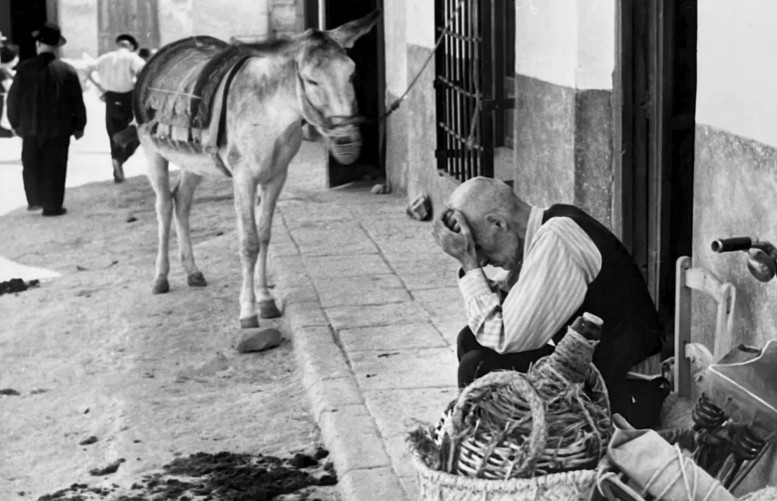 Padrí amb bicicleta, burro i tina ajagut en un pedrís: sembla el centre històric. 