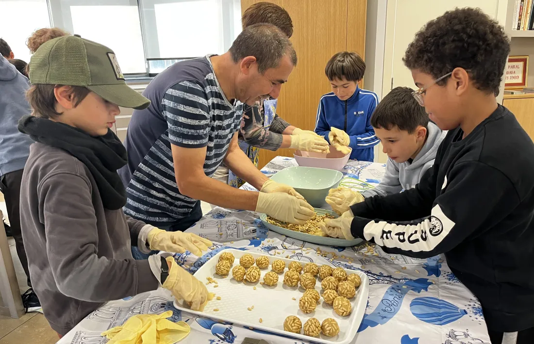 Els infants fent panellets guiats per la gent gran.