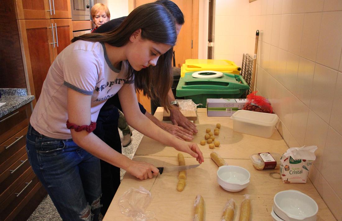 Joves i padrins fan panellets en un taller intergeneracional