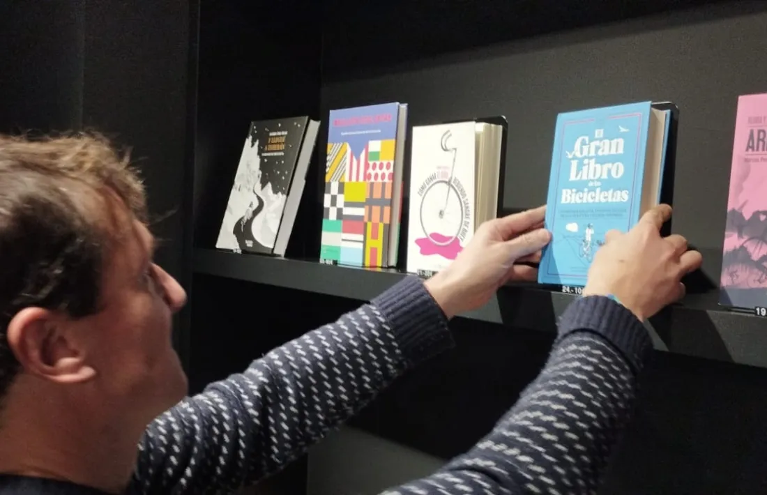 El cap del BiciLab, Edu Tarrés, col·loca a la prestatgeria 'El Gran Libro de las Bicicletas'.