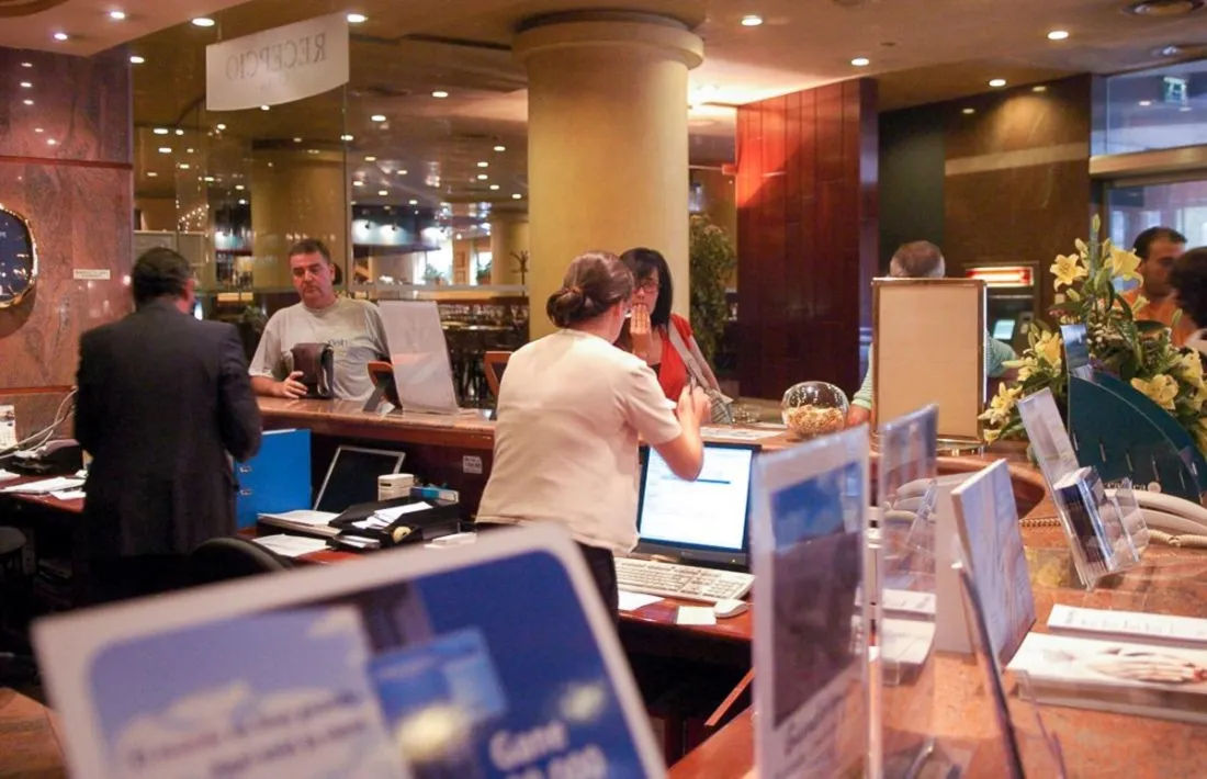 Recepcionistes d'un hotel atenent turistes. 