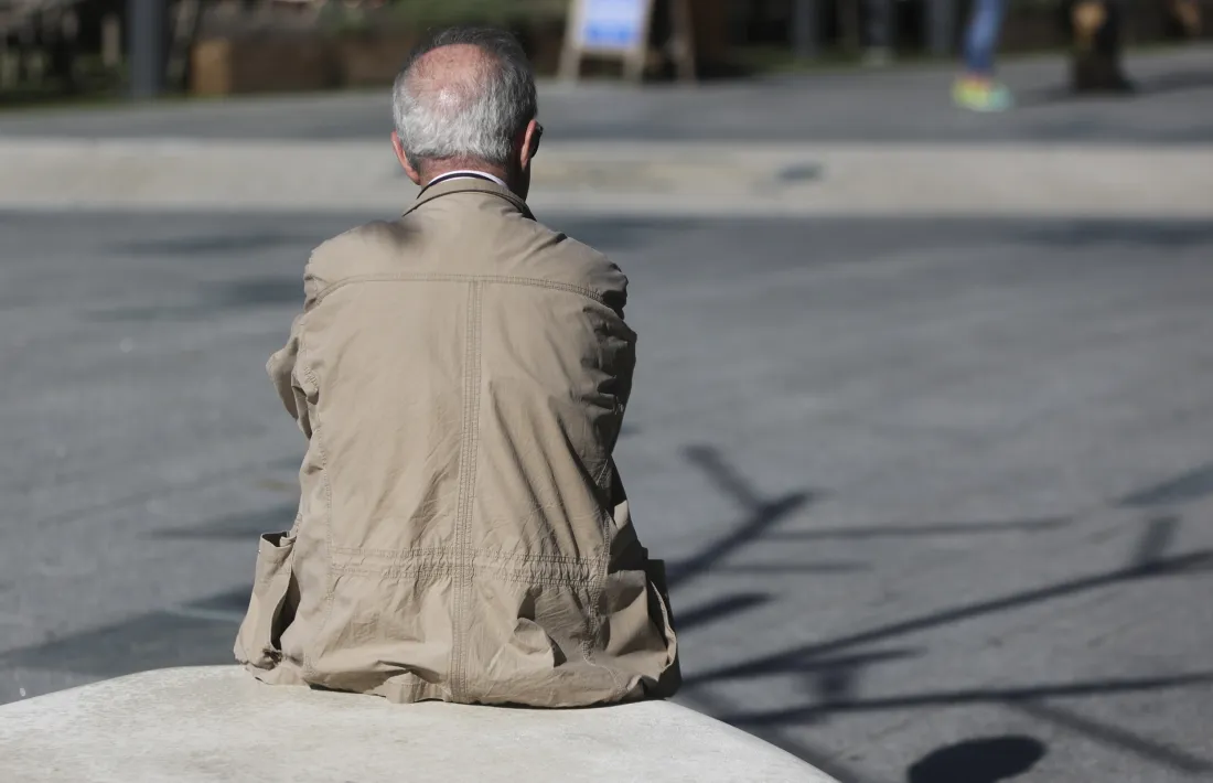 Un jubilat espera assegut en un element decoratiu de la plaça de la Rotonda d'Andorra la Vella.