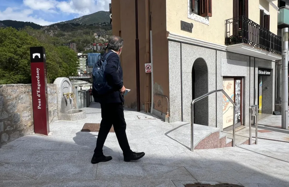 Una persona passa davant de l'accés a Caldes pel costat del riu.