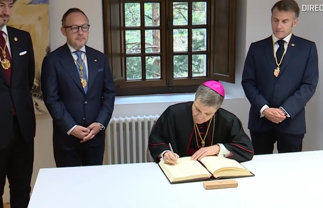 El copríncep episcopal, Josep-Lluís Serrano, signa el llibre d'or en presència de Macron, Espot i Ensenyat.