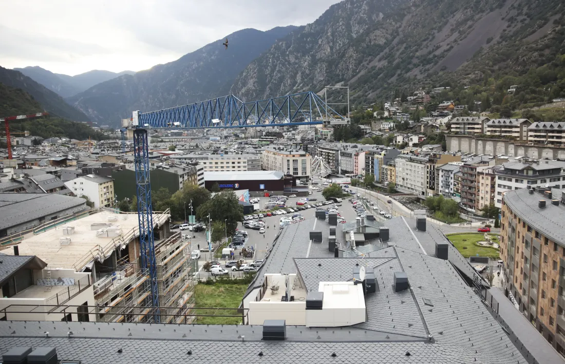 Vista d'Andorra la Vella amb una grua de construcció en primer pla.