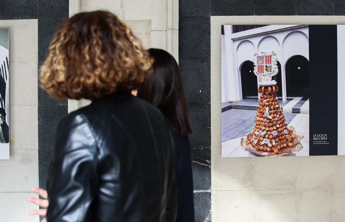 Dues dones visiten l'exposició amb la foto del pastis de lioneses a la dreta.